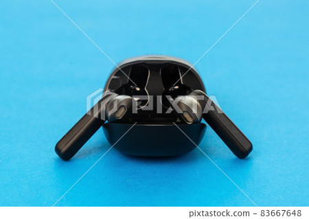 Modern wireless headphones in charging box on blue background 83667648