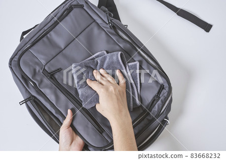 Cleaning backpack with washcloth. A person wipes off dirt or dust from the outside of the bag. Wiping school bag with damp cloth Cleaning backpack with washcloth. A person wipes off dirt or dust from the outside of the bag. Wiping school bag with damp cloth 83668232