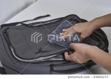 Cleaning backpack with washcloth. A person wipes off dirt or dust from the outside of the bag. Wiping school bag with damp cloth 83668237