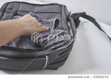 Cleaning backpack with washcloth. A person wipes off dirt or dust from the outside of the bag. Wiping school bag with damp cloth 83668238