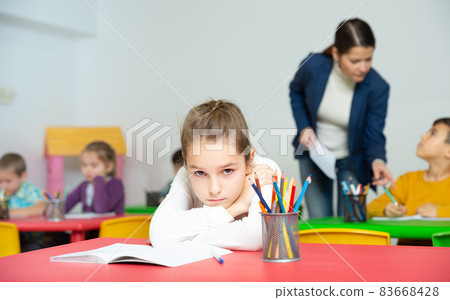Sad schoolgirl in classroom during lesson 83668428