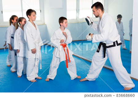 Teenagers are practicing on boxing paws with coach Teenagers are practicing on boxing paws with coach 83668660