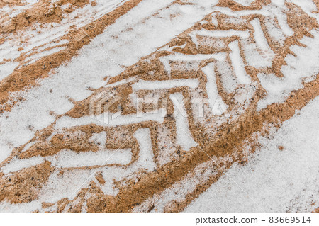 Traces and patterns from the tires of the wheels of industrial transport on the ground in winter background Traces and patterns from the tires of the wheels of industrial transport on the ground in winter background 83669514