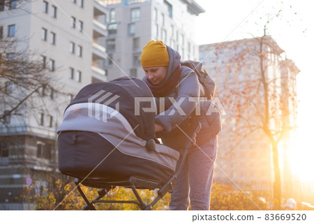 Happy young mother with pram during the walk 83669520