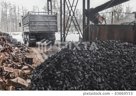 A dump truck at a landfill or on an industrial site unloaded a pile of coking coal from the body A dump truck at a landfill or on an industrial site unloaded a pile of coking coal from the body 83669553