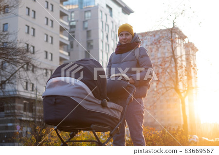 Happy young mother with pram during the walk Happy young mother with pram during the walk 83669567