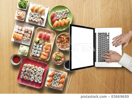 Businessman working on his laptop on wooden table with sushi and maki 83669689
