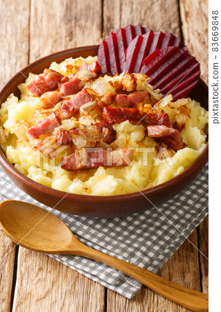 Braendende Kaerlighed or Burning love is an old danish dish with mashed potatoes, crisp bacon bits and soft fried onions close-up in a bowl. Vertical 83669848