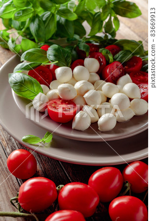 Caprese salad with tomato, mini mozzarella and basil on a old wooden table. 83669913