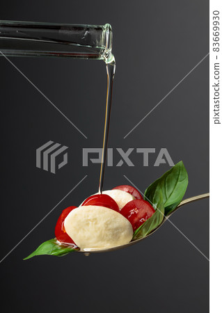 Mozzarella with tomato and basil is watered with vegetable oil. 83669930