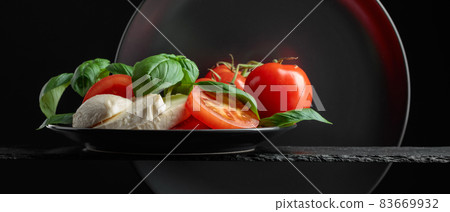 Mozzarella with tomato and basil on a black background. Mozzarella with tomato and basil on a black background. 83669932
