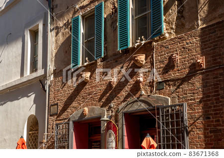 Castiglione del Lago Trasimeno, Umbria, Italy. August 2020. Amazing details of the facade of a house in the historic center: small statues animate the windows. Castiglione del Lago Trasimeno, Umbria, Italy. August 2020. Amazing details of the facade of a house in the historic center: small statues animate the windows. 83671368