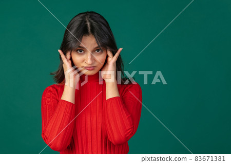 Half-length portrait of young cute girl, student in bright red sweater isolated on green studio backgroud. 83671381