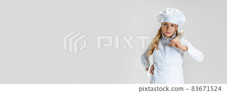 Flyer with little cute girl in white cook uniform and huge chef's hat posing isolated on white studio background. 83671524