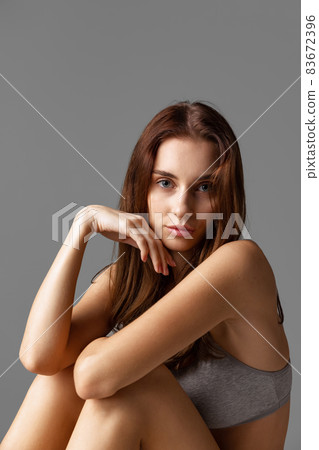 Close-up portrait of young beautiful girl without makeup isolated over gray studio background. Natural beauty concept. Close-up portrait of young beautiful girl without makeup isolated over gray studio background. Natural beauty concept. 83672396