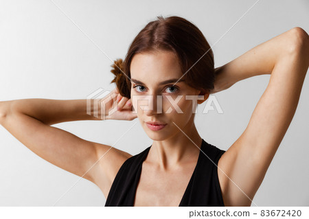 Close-up portrait of young beautiful girl without makeup isolated over gray studio background. Natural beauty concept. Close-up portrait of young beautiful girl without makeup isolated over gray studio background. Natural beauty concept. 83672420