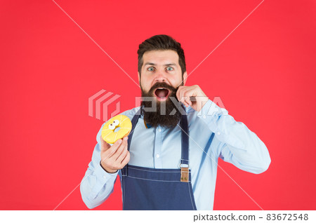 Bearded man in apron. Diet and healthy food. Doughnut Bearded man in apron. Diet and healthy food. Doughnut 83672548