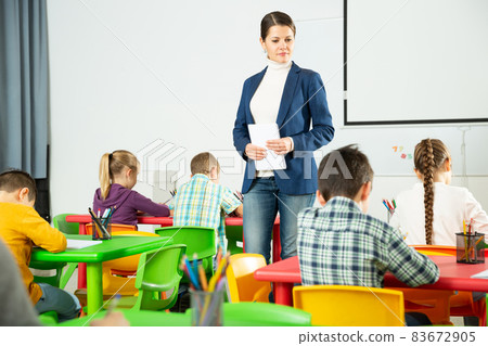 Teacher controlling writing of elementary school students 83672905