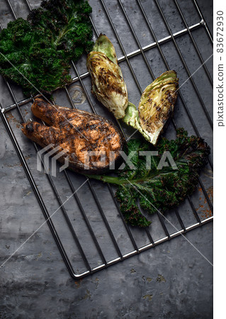 Grilled salmon steak and grilled vegetables on metal grid on grey clay background 83672930