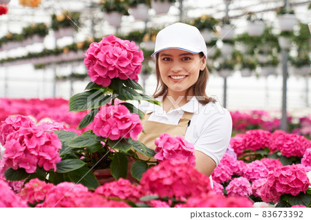Smiling young woman enjoying beauty bright flowers. 83673392
