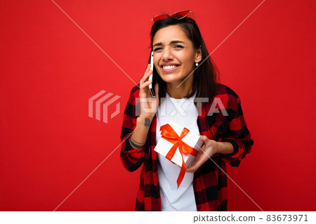 Shot of beautiful happy emotional young brunette woman isolated over red background wall wearing 83673971