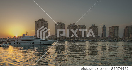 The pearl Marina in Doha , Qatar  at sunset with Yachts in foreground, buildings and clouds in the sky in background 83674482