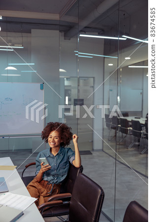 Happy Afro American woman sitting on chair in the meeting room Happy Afro American woman sitting on chair in the meeting room 83674585