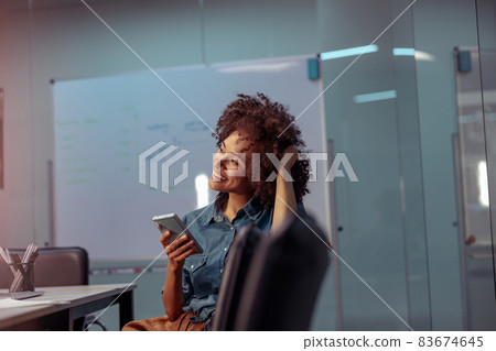 Smiling young lady using mobile phone in the office 83674645