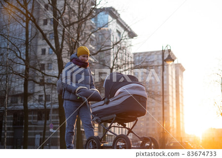 Happy young mother with pram during the walk 83674733