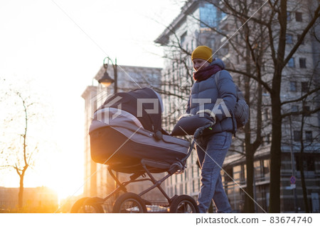 Happy young mother with pram during the walk 83674740