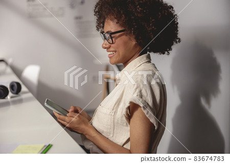 Smiling businesswoman looking at phone screen in the office Smiling businesswoman looking at phone screen in the office 83674783