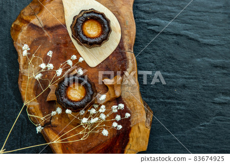 Canneles (Caneles) de Bordeaux Recipe is a small pastry with rum and vanilla on a wooden plate. Canneles (Caneles) de Bordeaux Recipe is a small pastry with rum and vanilla on a wooden plate. 83674925