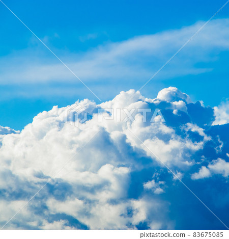 White fluffy cumulus clouds on the clear blue sky in the sunshine. Top view from the plane. Background for design. Square photo 83675085