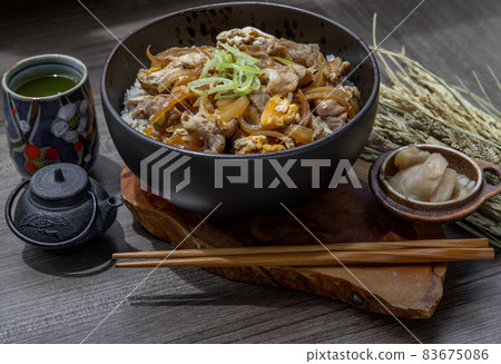 Japanese pork rice bowl with egg and onion (Donburi) served with pickled ginger and green tea. Japanese pork rice bowl with egg and onion (Donburi) served with pickled ginger and green tea. 83675086