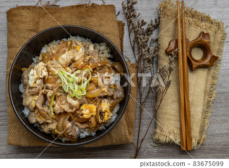 Japanese pork rice bowl with egg and onion (Donburi) served with pickled ginger and green tea. Japanese pork rice bowl with egg and onion (Donburi) served with pickled ginger and green tea. 83675099