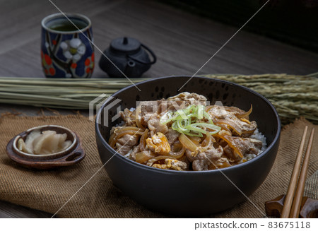 Japanese pork rice bowl with egg and onion (Donburi) served with pickled ginger and green tea. 83675118