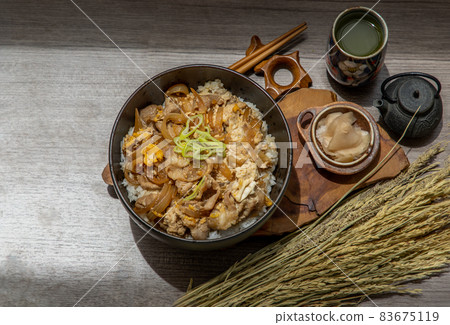 Japanese pork rice bowl with egg and onion (Donburi) served with pickled ginger and green tea. 83675119