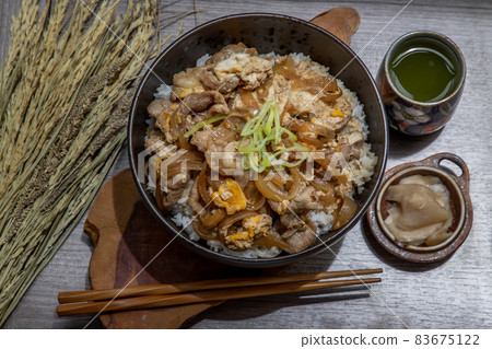 Japanese pork rice bowl with egg and onion (Donburi) served with pickled ginger and green tea. Japanese pork rice bowl with egg and onion (Donburi) served with pickled ginger and green tea. 83675122