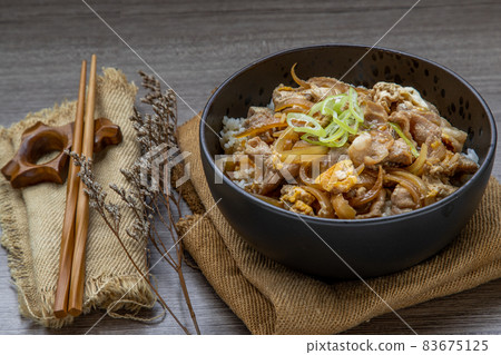 Japanese pork rice bowl with egg and onion (Donburi) served with pickled ginger and green tea. Japanese pork rice bowl with egg and onion (Donburi) served with pickled ginger and green tea. 83675125