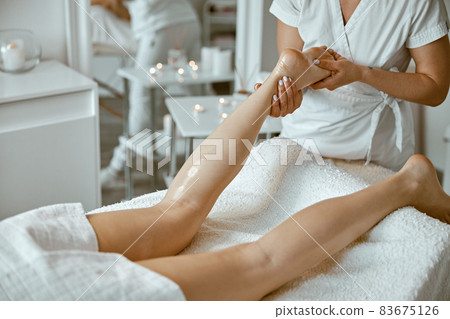 Professional caucasian specialist is doing leg message at modern minimalistic salon Professional caucasian specialist is doing leg message at modern minimalistic salon 83675126
