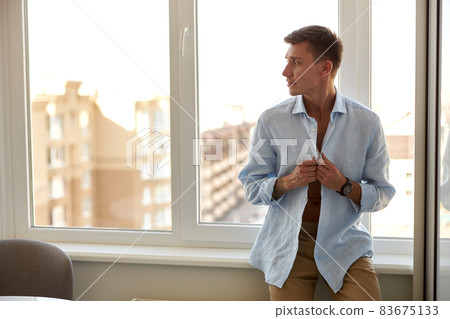 Happy beautiful handsome smiling caucasian man is relaxing at modern light home Happy beautiful handsome smiling caucasian man is relaxing at modern light home 83675133
