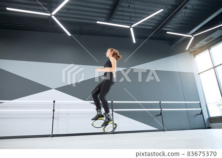 Young athlete practicing kangoo jumps in hall. 83675370