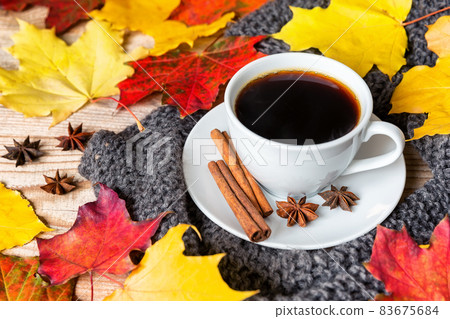 Cozy autumn morning with cup of coffee with cinnamon, star anise, cozy sweater and autumn leaves on wooden background. Cozy autumn morning with cup of coffee with cinnamon, star anise, cozy sweater and autumn leaves on wooden background. 83675684