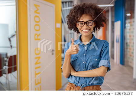 Multiethnic young lady holding thumb up in coworking Multiethnic young lady holding thumb up in coworking 83676127