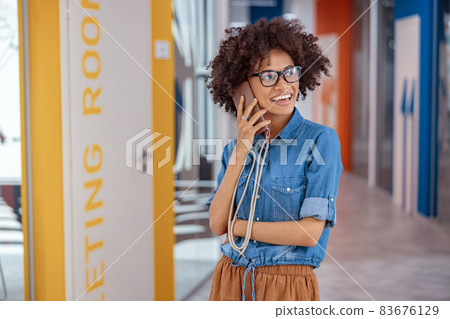 Happy young lady having a conversation on the phone in office hall 83676129