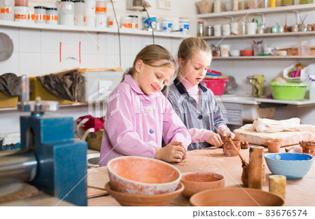 Smiling schoolgirls training to make ceramics during arts Smiling schoolgirls training to make ceramics during arts 83676574