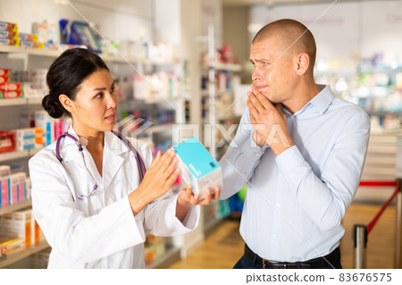 Man asks to help pharmacist choose medicine for toothache Man asks to help pharmacist choose medicine for toothache 83676575