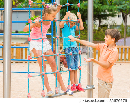 Kids are climbing on the grid on the playground. Kids are climbing on the grid on the playground. 83676576