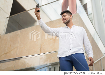 Young handsome hispanic man taking selfie with smartphone outdoors. 83676832