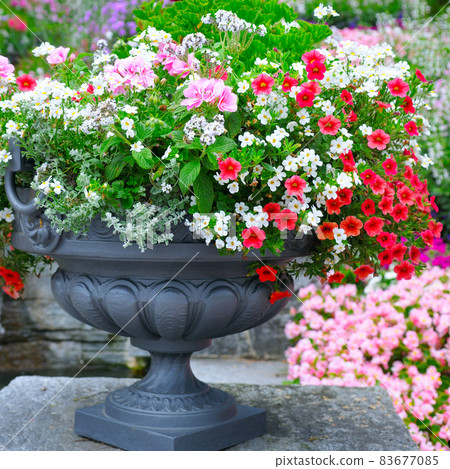 Beautiful flower arrangement in a metal vase in a summer park. 83677085